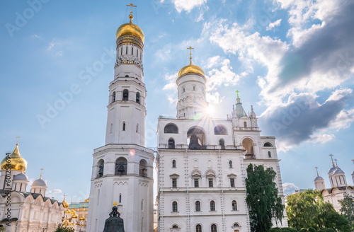 Ivan the Great Bell Tower, with Assumption Belfry on the right in Moscow Kremlin. Blue sky background with sunbeams