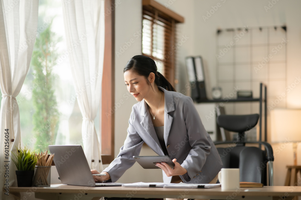 Young Asian businesswoman reading graphs and talking on phone with customers in office Young Asian businesswoman reading graphs and talking on phone with customers in office