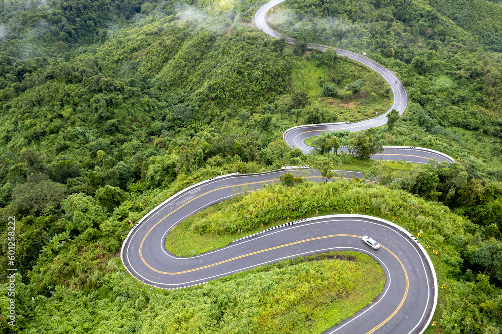 Top view of countryside road passing through the green forrest and mountain Top view of countryside road passing through the green forrest and mountain