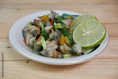 selective focus on white bowl serving sea snail or Laevistrombus canarium in Indonesian is called siput gonggong. soft focus photo