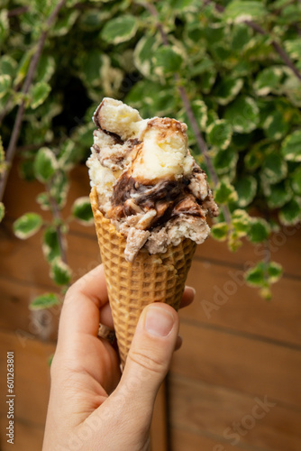 Female hand holding delicious american vanilla chocolate ice cream. Tasty homemade icecream Gelato in the waffle cone. Gluten free vegan dairy free ice cream. 