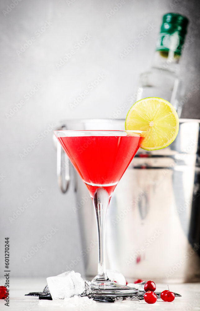 Cosmopolitan alcoholic cocktail drink with vodka, liqueur, cranberry juice, lime and ice. Gray table background, bar tools, copy space Cosmopolitan alcoholic cocktail drink with vodka, liqueur, cranberry juice, lime and ice. Gray table background, bar tools, copy space