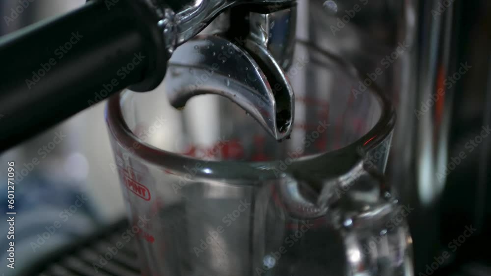 Close up while shot of Espresso Pouring from both Sides of an Espresso Maker machine spout pouring into a small Coffee cup Mug for fresh aromatic espresso Close up while shot of Espresso Pouring from both Sides of an Espresso Maker machine spout pouring into a small Coffee cup Mug for fresh aromatic espresso