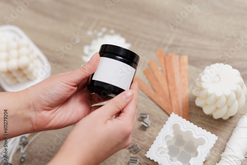 Woman hand holding handmade soy candle jar with white label with space for text photo