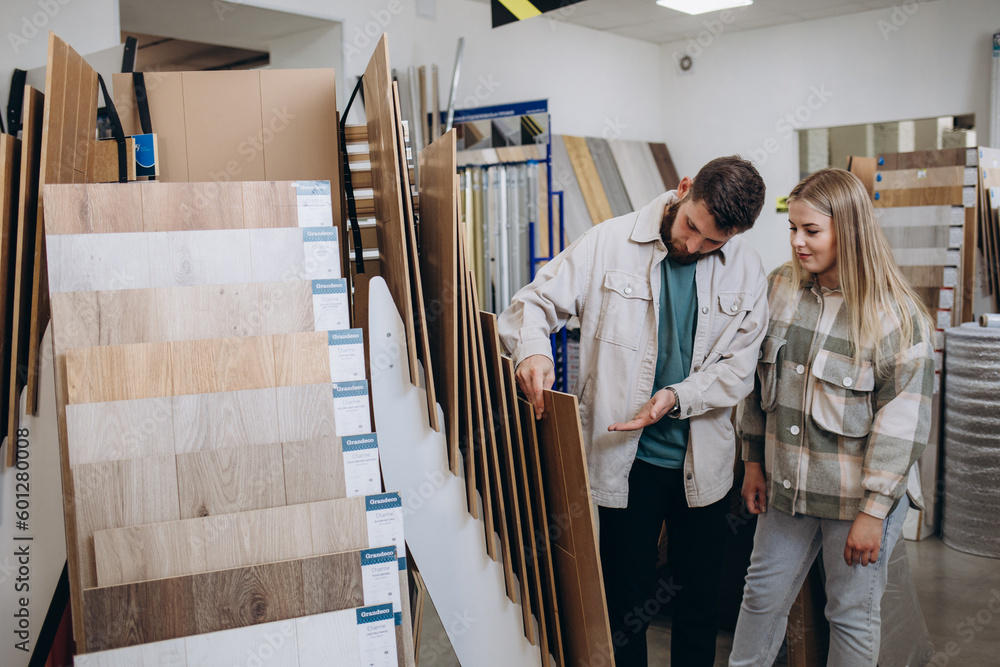 Young family couple choosing laminated material for home in modern store.