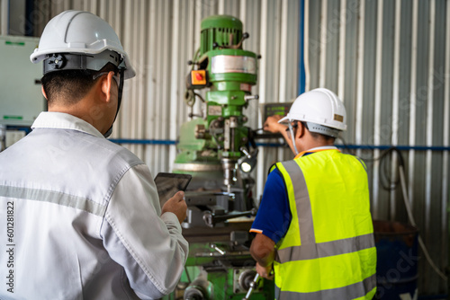 Asian engineer checking worker operating lathe grinding machine - metalworking industry concept. Mechanical Engineering control lathe machine in factory.