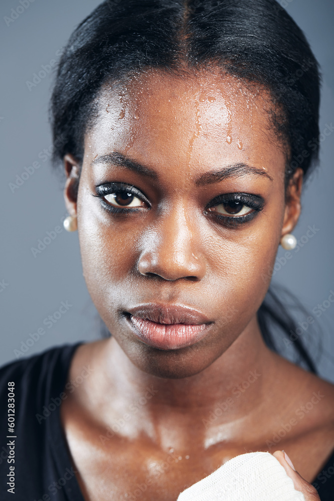 Obraz premium Portrait, boxing and a woman sweating in studio on a gray background for self defense, fitness or training. Face, exercise and workout with a black female boxer practising for a fighting competition