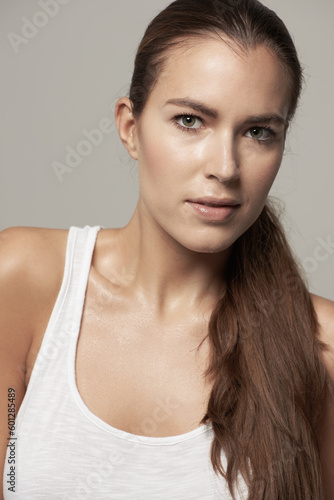 Serious woman, portrait and natural beauty in skincare or facial cosmetics against grey studio background. Isolated female person, face or model in cosmetic haircare in active sportswear on backdrop