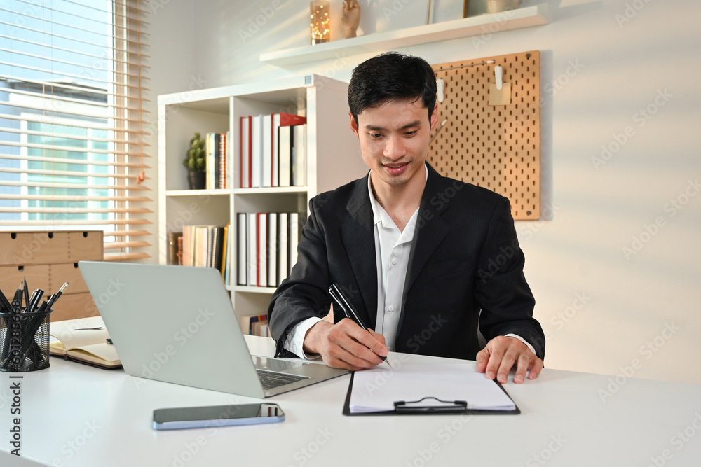 Image of professional businessman in formalwear writing his strategy, signing a contract at working desk Image of professional businessman in formalwear writing his strategy, signing a contract at working desk