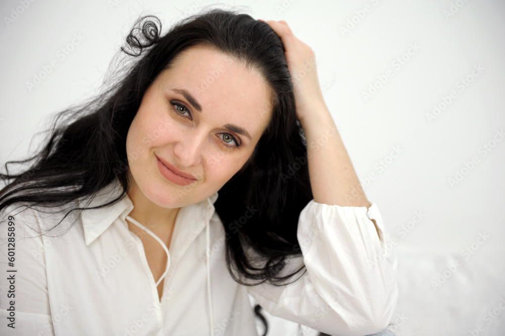 Portrait of a young successful woman with dark hair. The woman straightens her hair with her hands. High quality photo Portrait of a young successful woman with dark hair. The woman straightens her hair with her hands. High quality photo