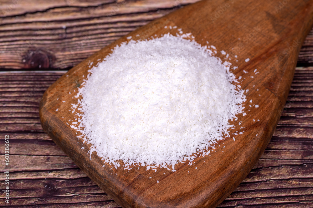 Coconut powder. Grounded coconut flakes on a wood flipchart. dessicated coconut Coconut powder. Grounded coconut flakes on a wood flipchart. dessicated coconut
