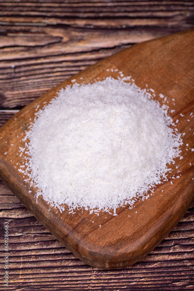 Coconut powder. Grounded coconut flakes on a wood flipchart. dessicated coconut. Close up