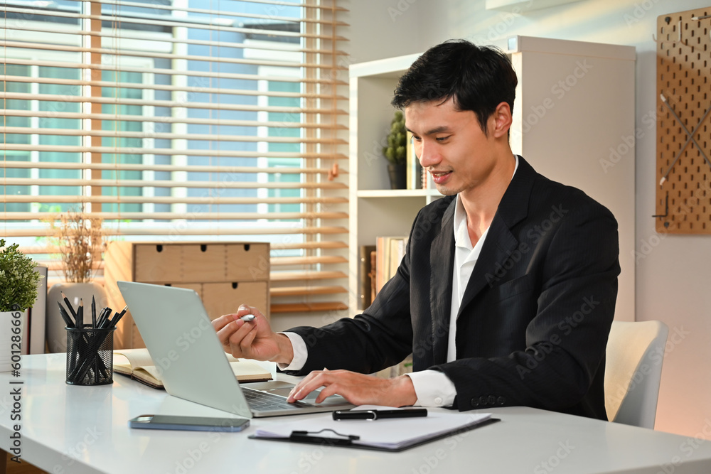 Asian male entrepreneur using laptop computer, working online sale marketing at modern workplace Asian male entrepreneur using laptop computer, working online sale marketing at modern workplace