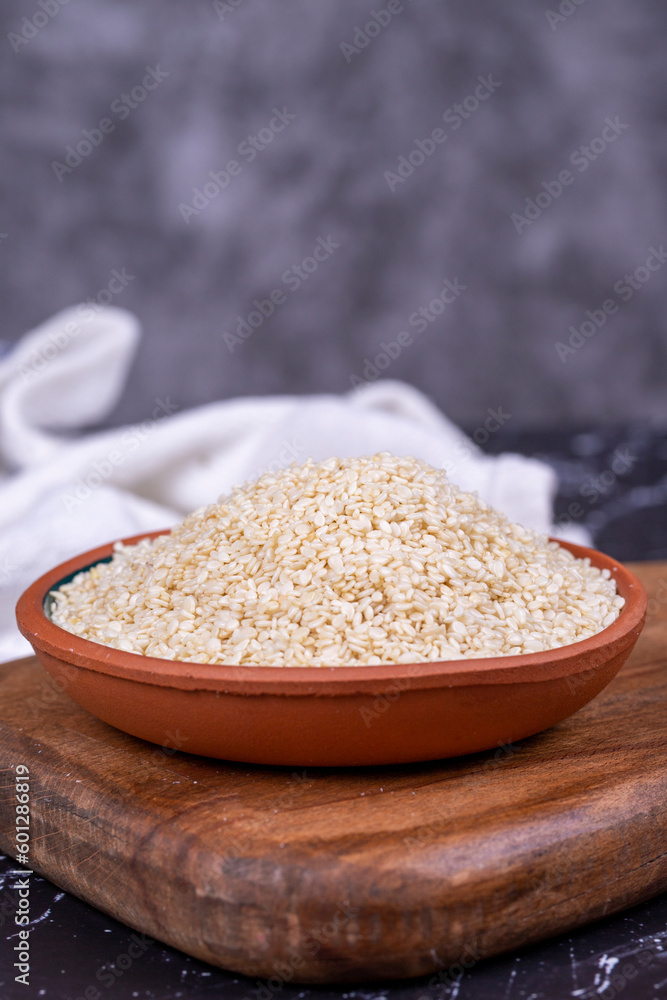 Sesame seeds on dark background. Organic White Sesame seeds (Sesamum indicum) in Earthen bowl. Close up Sesame seeds on dark background. Organic White Sesame seeds (Sesamum indicum) in Earthen bowl. Close up