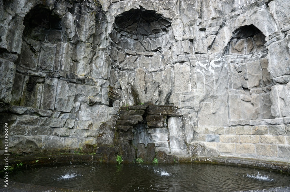 Fontänenbrunnen vor grauem alten Felsgemäuer 
