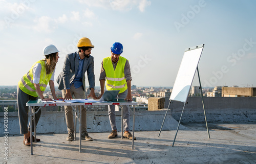 Diverse team of specialists with computer on construction site. Building project with engineers
