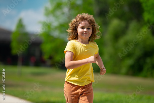 Cute kid boy running across american neighborhood street. Summer, childhood, leisure and people concept. Happy little blonde child boy running in summer park outdoor. Sport and run. © Volodymyr
