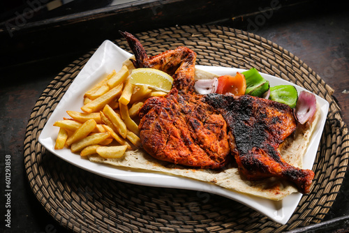 Full Chicken Grill with fries and salad served in dish isolated on red mat top view on table arabic food