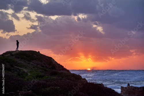 Scenic sunset with a lonely figure on a hill at the Mediterranean