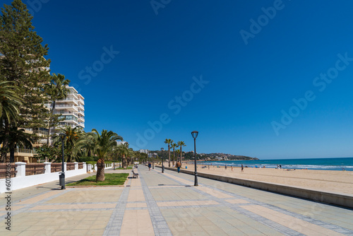 The promenade of the Mediterranean Sea on a sunny day in spring. Palm trees and benches among stylish houses in the province of Castellon