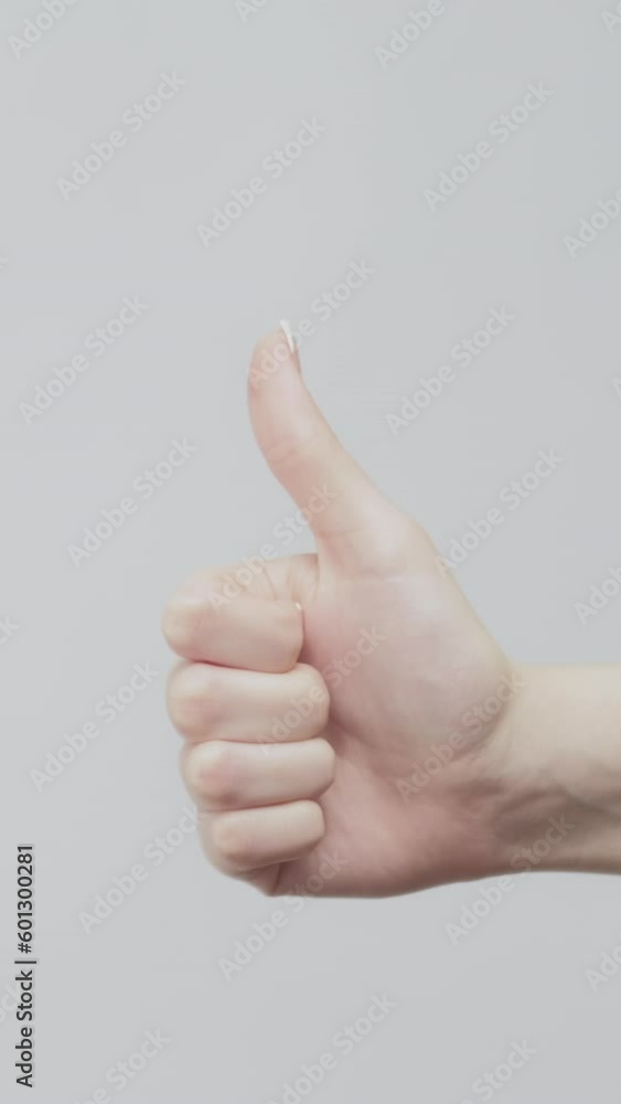 Vertical video. Like gestures. Perfect choice. Female hand showing thumb up set of 2 signs on light background. Vertical video. Like gestures. Perfect choice. Female hand showing thumb up set of 2 signs on light background.