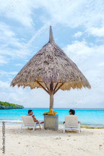 A couple of men and women on vacation in Curacao  Cas Abao Beach Playa Cas Abao Caribbean island of Curacao  Playa Cas Abao tropical white beach with beach chairs and a blue turqouse colored ocean. 