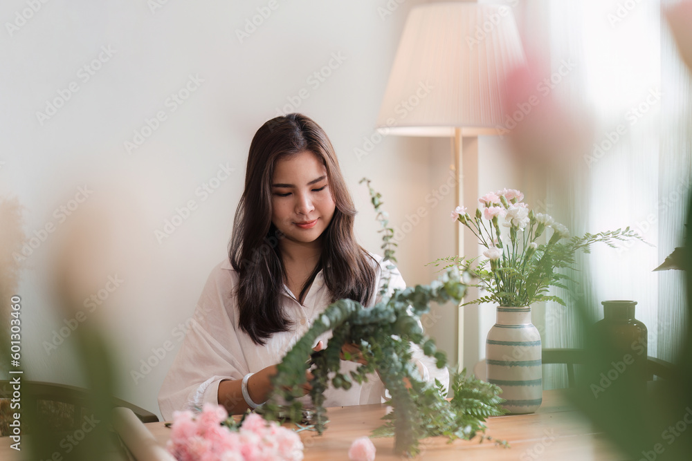 Startup, small business, flower shop. Young pretty florist putting a flower on a vase Startup, small business, flower shop. Young pretty florist putting a flower on a vase