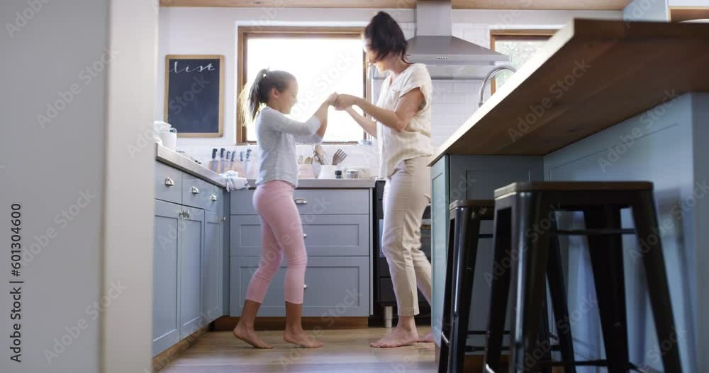 Mother, girl and dancing in the kitchen with happiness and freedom in family home. Mom, child and dance with music holding hands for growth as a dancer in the morning with energy for happy lifestyle. Mother, girl and dancing in the kitchen with happiness and freedom in family home. Mom, child and dance with music holding hands for growth as a dancer in the morning with energy for happy lifestyle.