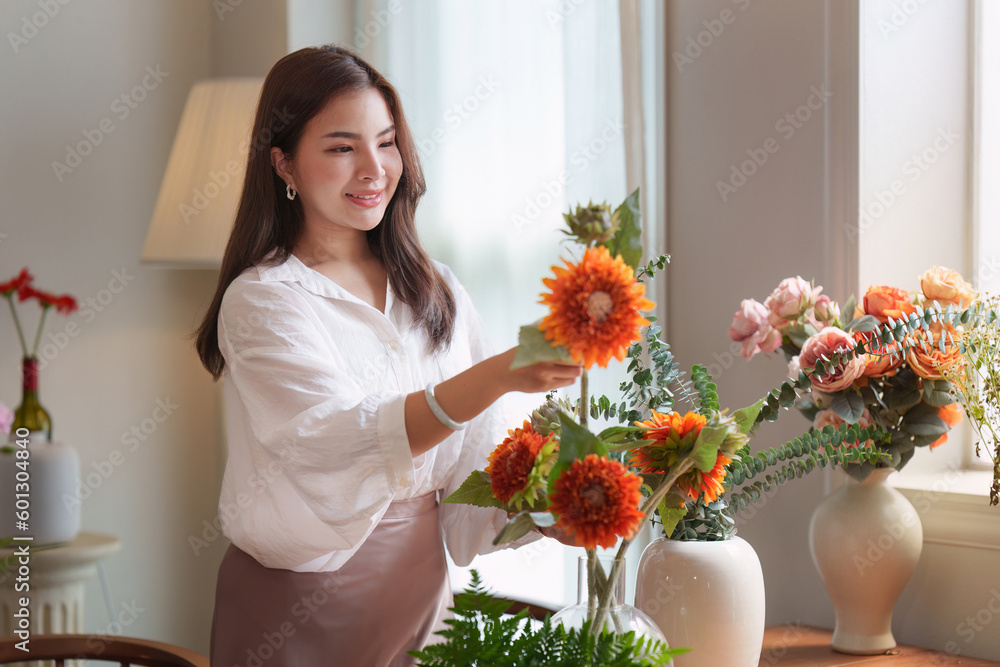 Startup, small business, flower shop. Young pretty florist putting a flower on a vase Startup, small business, flower shop. Young pretty florist putting a flower on a vase