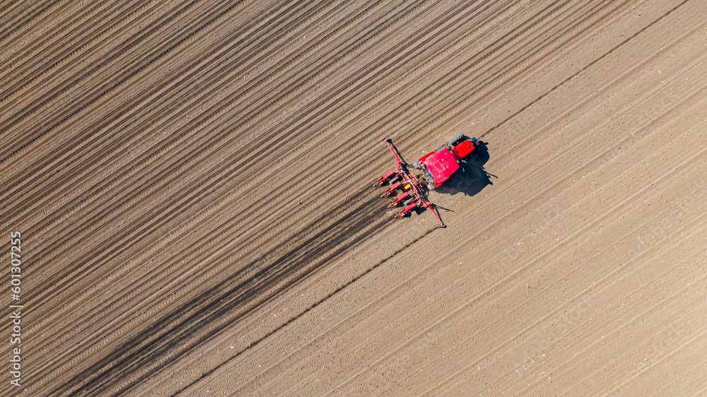 Aerial top view of tractor as dragging a sowing machine over agricultural field, farmland Aerial top view of tractor as dragging a sowing machine over agricultural field, farmland
