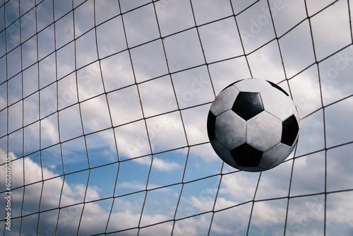 Symbolic of success and victory. classic soccer ball football have black and white color going into in-goal net after shooted in the game with a blue sky background. success concept.