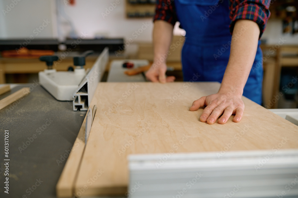 Closeup of carpenter cutting wooden board on circular saw workbench Closeup of carpenter cutting wooden board on circular saw workbench