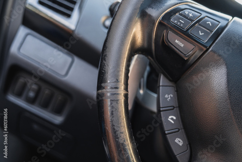 Shabby automotive black leather steering wheel of old auto close-up