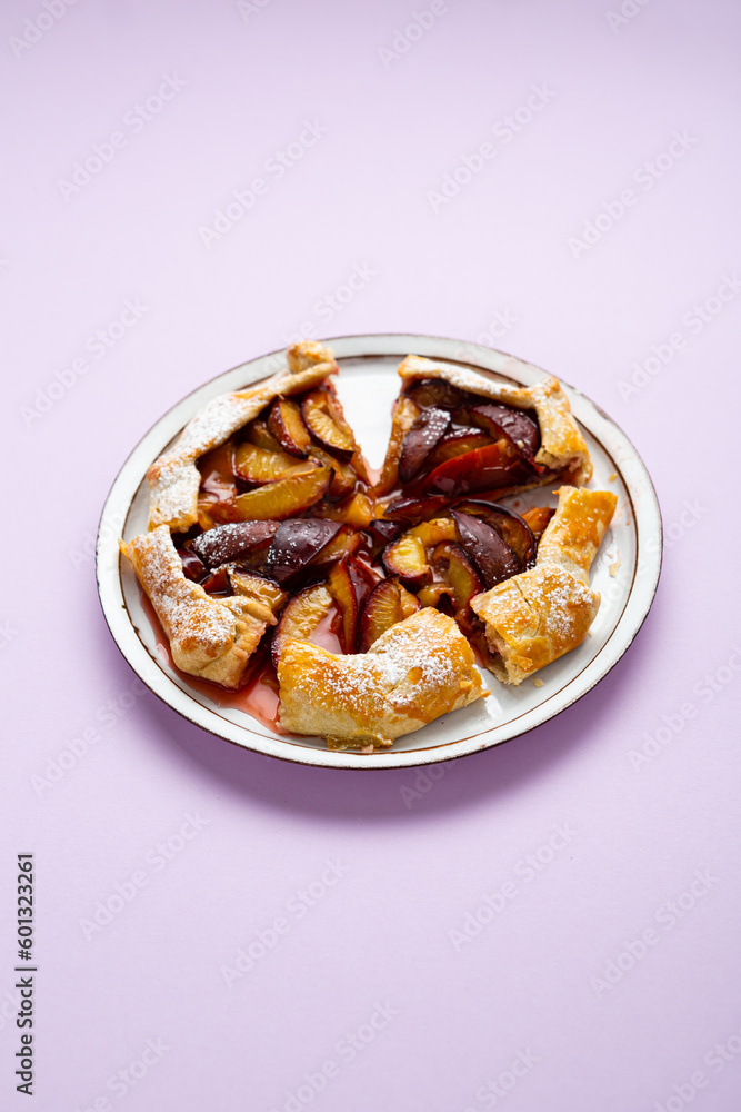 Overhead view of sliced summer plum pie tart on purple surface Overhead view of sliced summer plum pie tart on purple surface