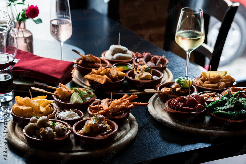Tapas Bowls with Food arranged on a Table in a Tapas Bar. - obrazy, fototapety, plakaty 