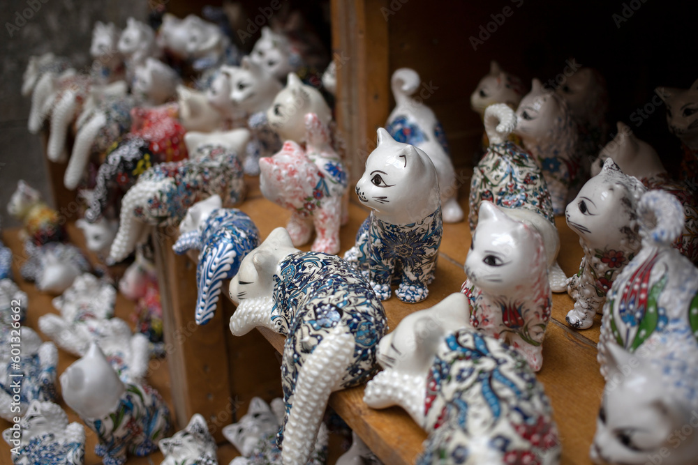 Plenty of porcelain cat figurines lined up on a shelf in a gift shop