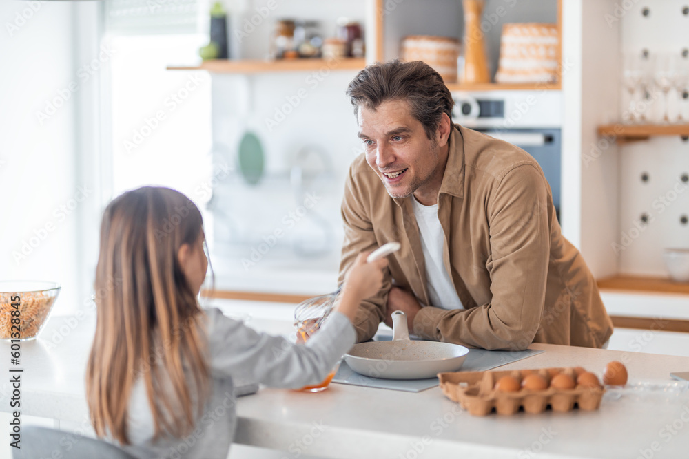 A caring father watching his cute girl beating yolks for a breakfast meal. A caring father watching his cute girl beating yolks for a breakfast meal.