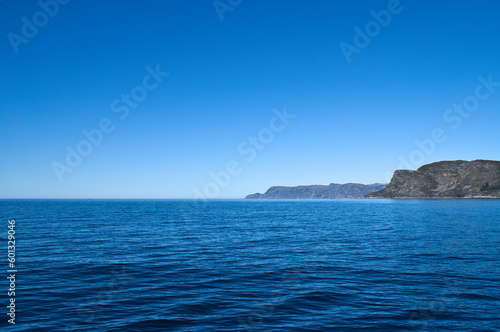 View from the sea to the West Cape in Norway in sunshine. Waves and rocks © Martin