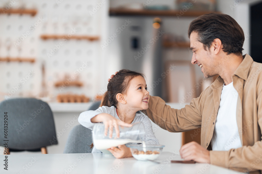 A smiling daughter and father looking at each other during breakfast time.