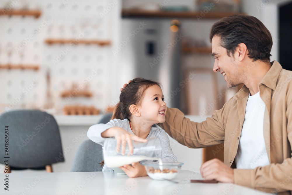 A smiling daughter and father looking at each other during breakfast time. A smiling daughter and father looking at each other during breakfast time.