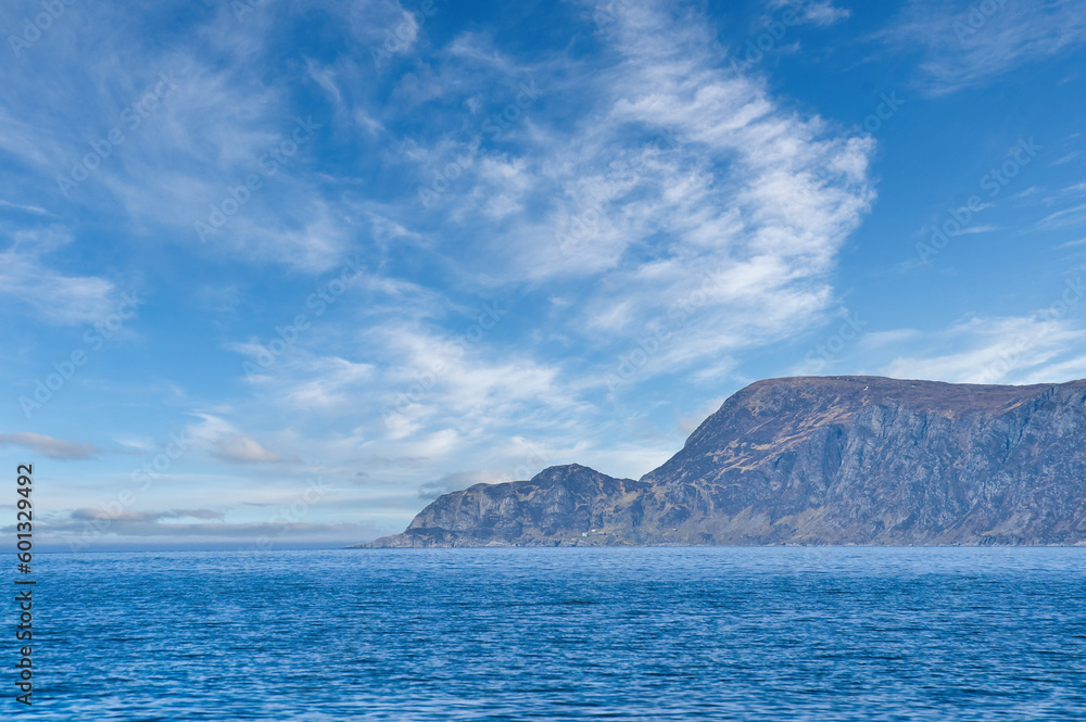 View from the sea to the West Cape in Norway in sunshine with light clouds
