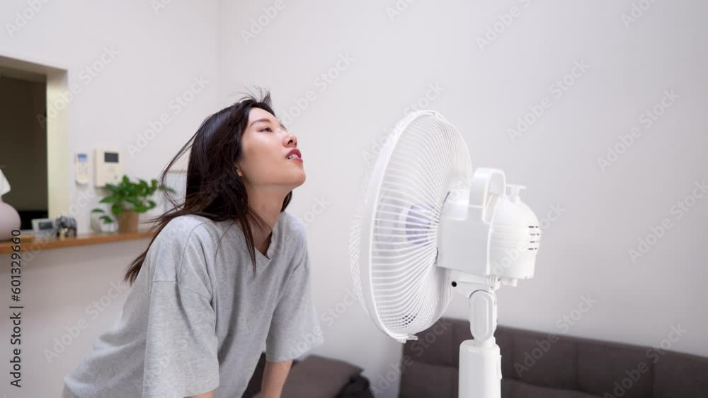 暑い夏の日に扇風機の風にあたって涼む若い女性 Stock Video | Adobe Stock