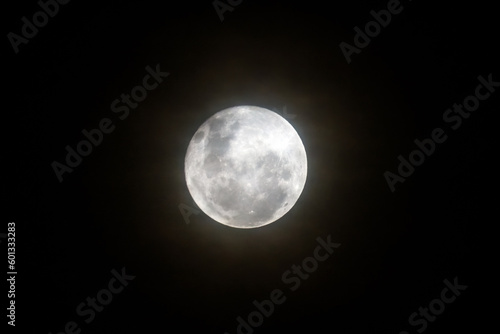 The Full Moon rising amongst the high cloud in the cold night air sky