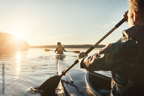 Kayak, lake and people rowing a boat on the water during summer for recreation or leisure at sunset. Nature, view and horizon with people canoeing for adventure, freedom or travel while on vacation