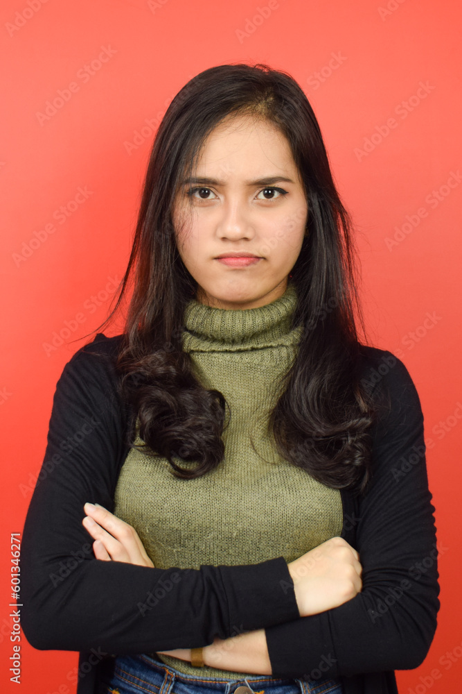 Folding arms and Angry Face Expression Of Beautiful Asian Woman Isolated On Red Background