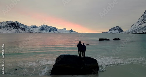 Pullback Over Haukland Beach With Couple Standing On Rock In Lofoten Archipelago, Northern Norway. Aerial Shot photo