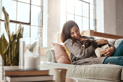 Smile, dog and woman on a couch, relax and love with joy, playful and carefree at home. Female person, girl and lady on a sofa, pet and happiness on a sofa, freedom and break with a domestic animal