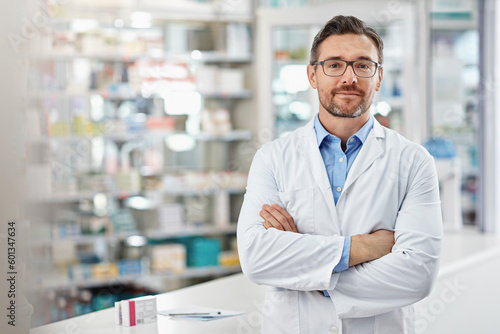 Healthcare, crossed arms and portrait of a male pharmacist standing in a pharmacy clinic. Pharmaceutical, medical and mature man chemist with confidence by the counter of medication store dispensary. photo