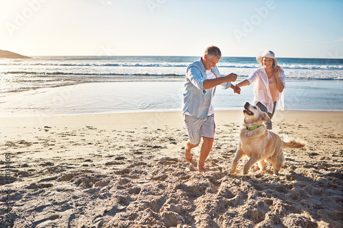 Happy couple, holding hands and at the beach with a dog in summer for retirement travel in Indonesia Fototapet