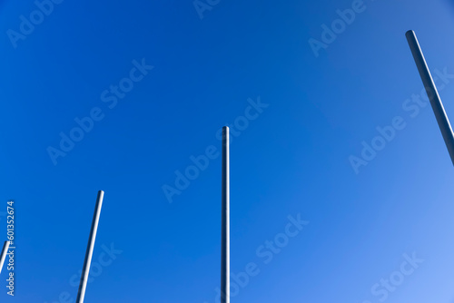 Tableau sur toile a group of empty metal flagpoles against a blue sky background